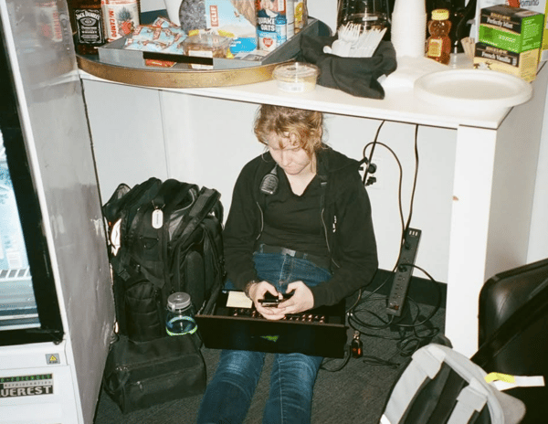 Emily working under the table of an arena green room in 2024 - credit @deaniechen on IG